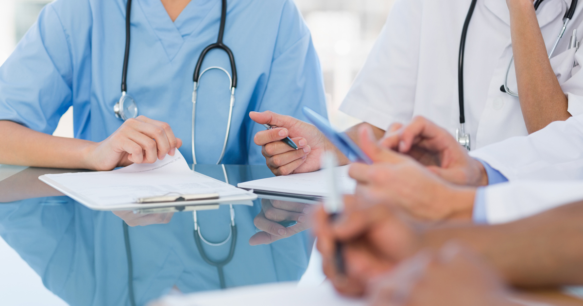 Physicians around a table discussing paperwork