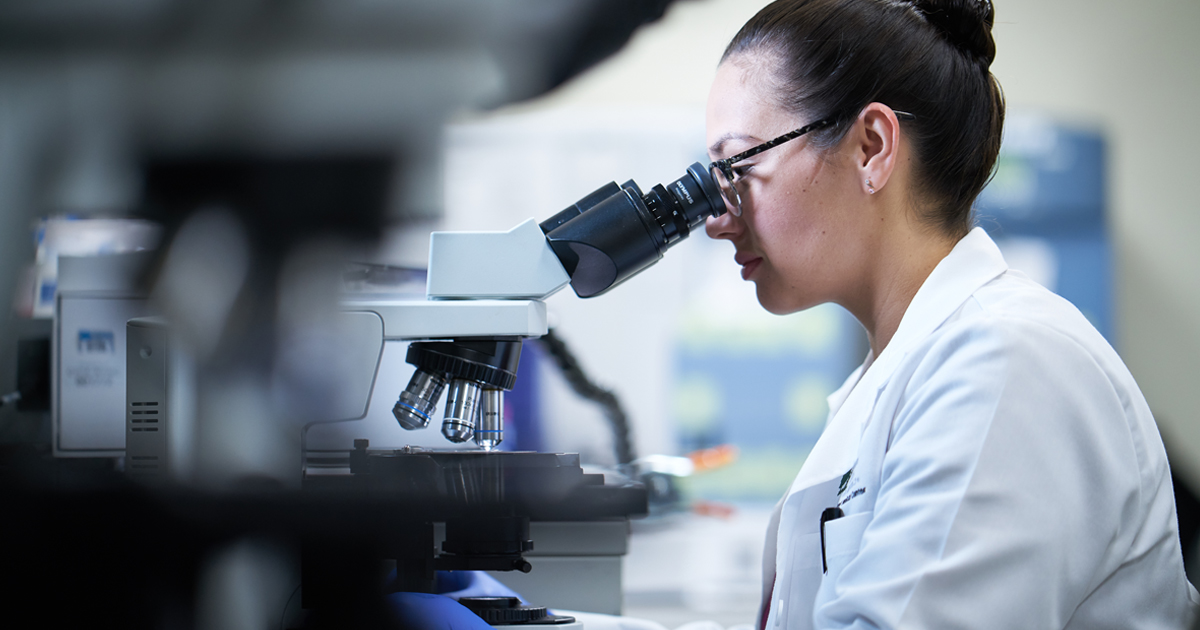 A scientist in the lab observing a virus through a microscope