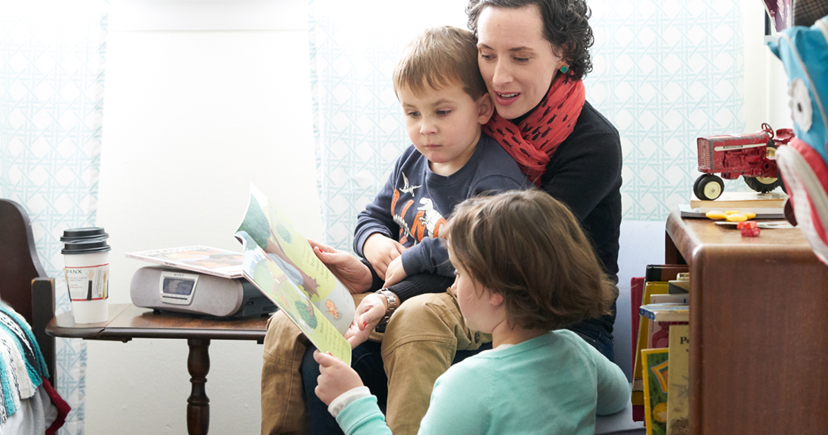 A mother reading a book about cancer with her children