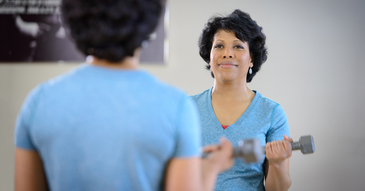 A female cancer patient lifting dumbbells to build muscle