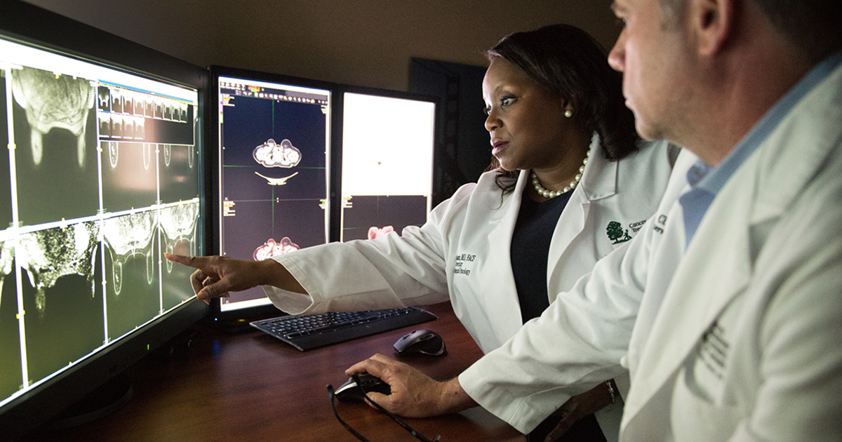 A male and female physician evaluating x-rays for a cancer diagnosis